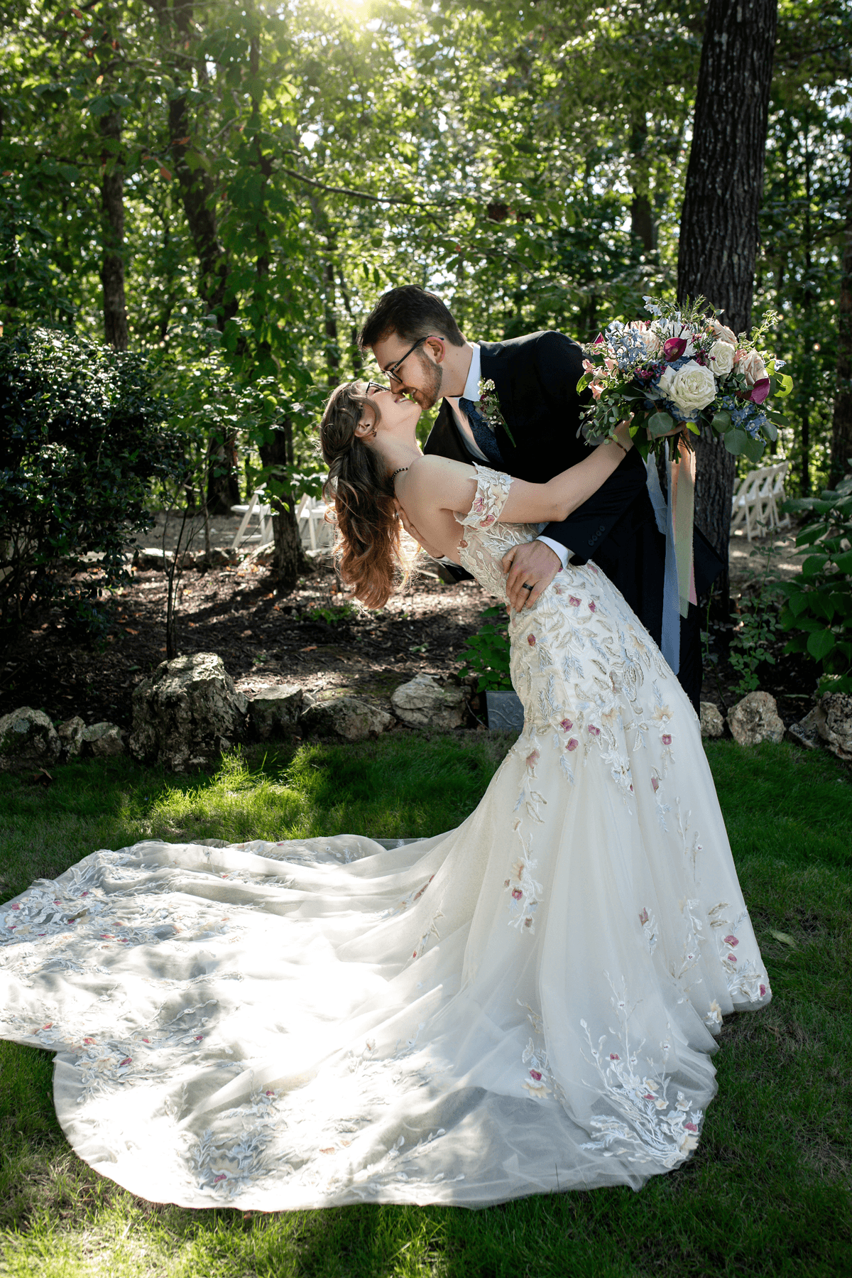 A bride and groom share a romantic kiss in a lush garden, surrounded by nature.