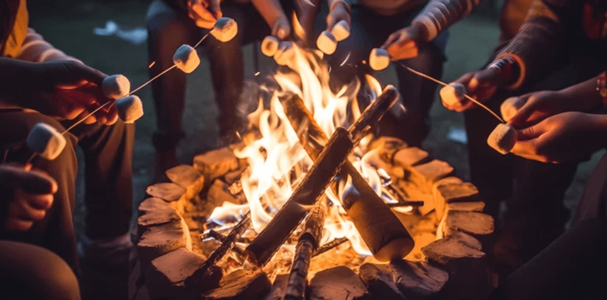 Hands holding marshmallows on sticks over a campfire. Hands holding marshmallows on sticks over a campfire.