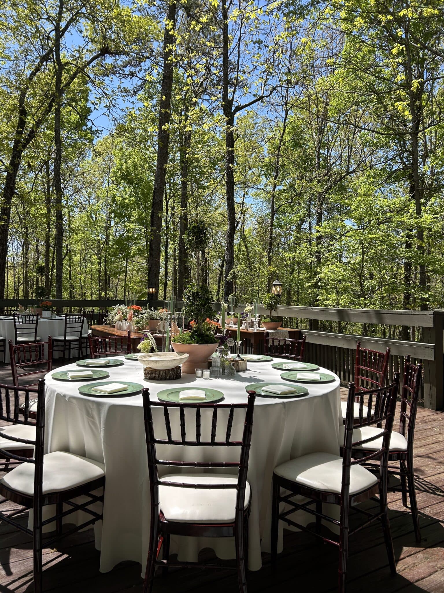 A beautifully set outdoor table surrounded by lush greenery and blue skies. A beautifully set outdoor table surrounded by lush greenery and blue skies.