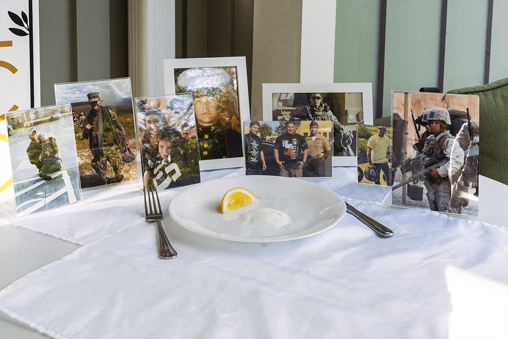 A table setting featuring framed photographs of soldiers and a plate of salt with a lemon slice.