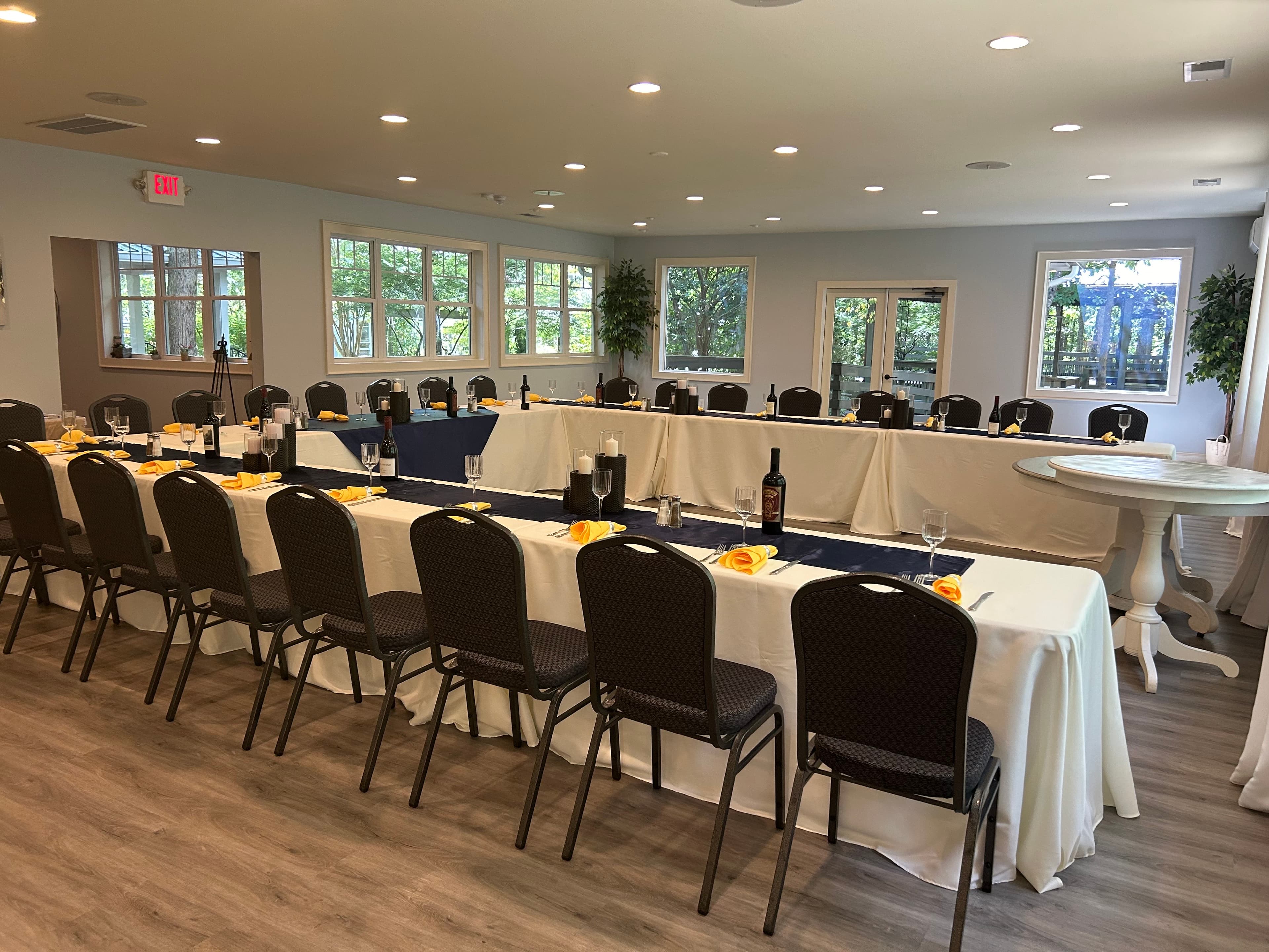 A neatly arranged dining room featuring long tables set with yellow napkins and decorative tableware.